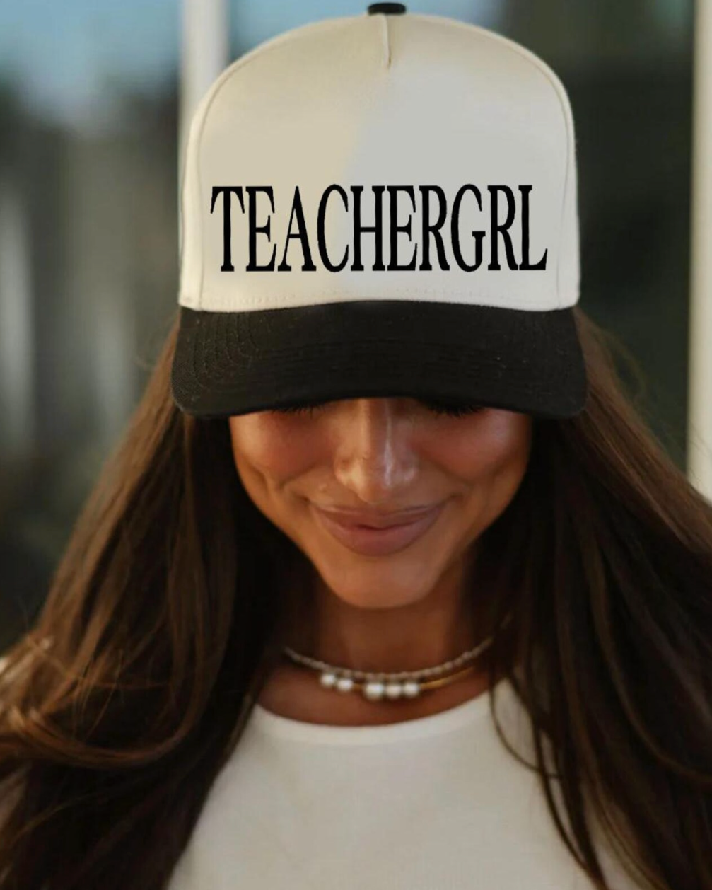 Woman wearing a cap with 'TEACHERGRL' text