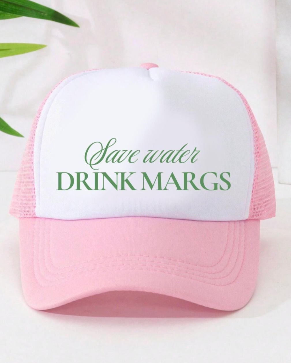 Pink and white cap with 'Save water DRINK MARGS' text on a light background