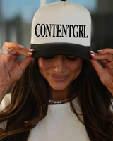 Person wearing a cap with 'CONTENTGIRL' text, with a blurred background