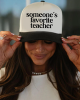 Person wearing a cap with 'someone's favorite teacher' text
