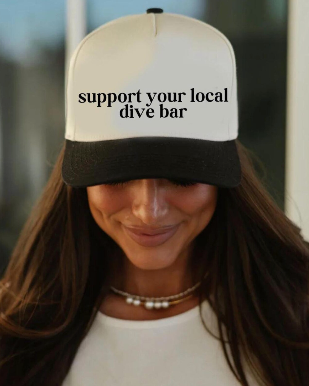 Person wearing a cap with 'support your local dive bar' text