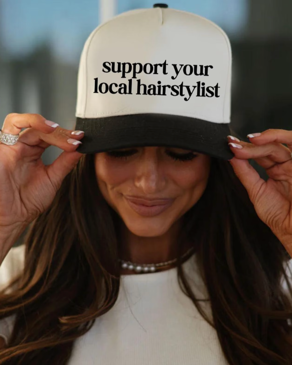 Person wearing a cap with 'support your local hairstylist' text