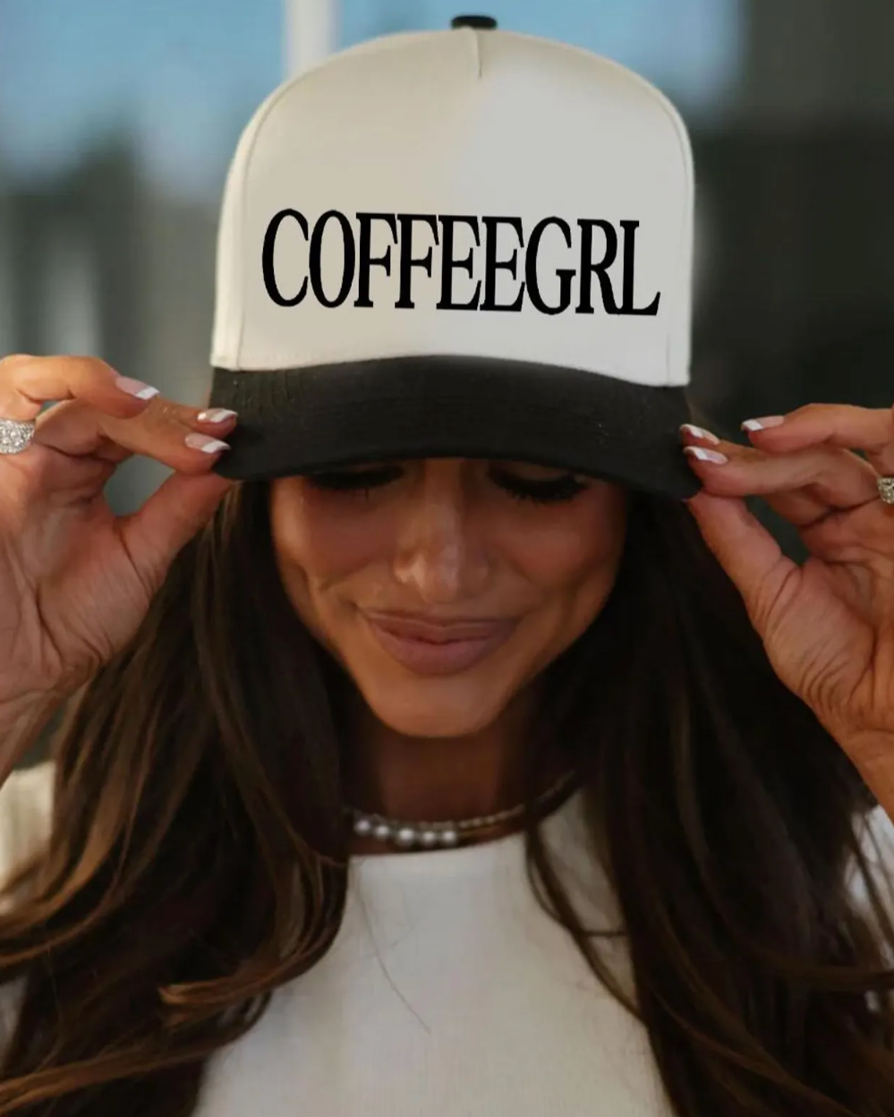 Person wearing a cap with 'COFFEEGRL' text, blurred background