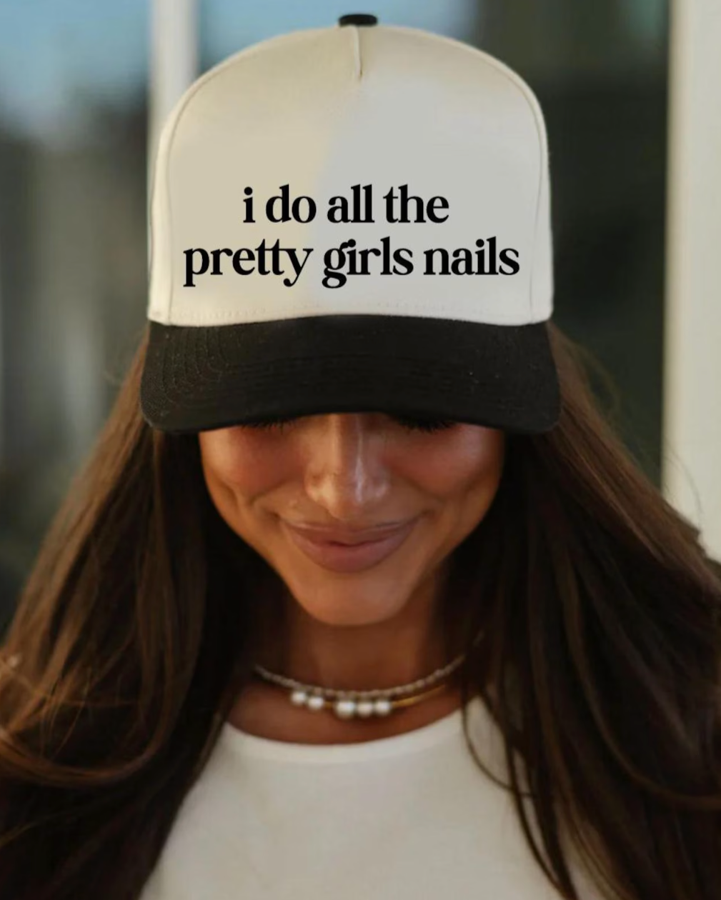 Person wearing a cap with 'i do all the pretty girls nails' text