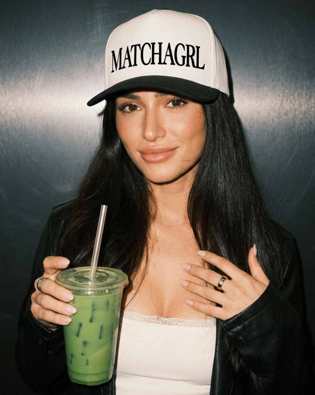 Person wearing a cap with 'MATCHAGRL' text, holding a green drink.