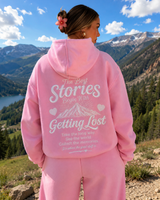 Person wearing a pink hoodie with text in a mountainous landscape
