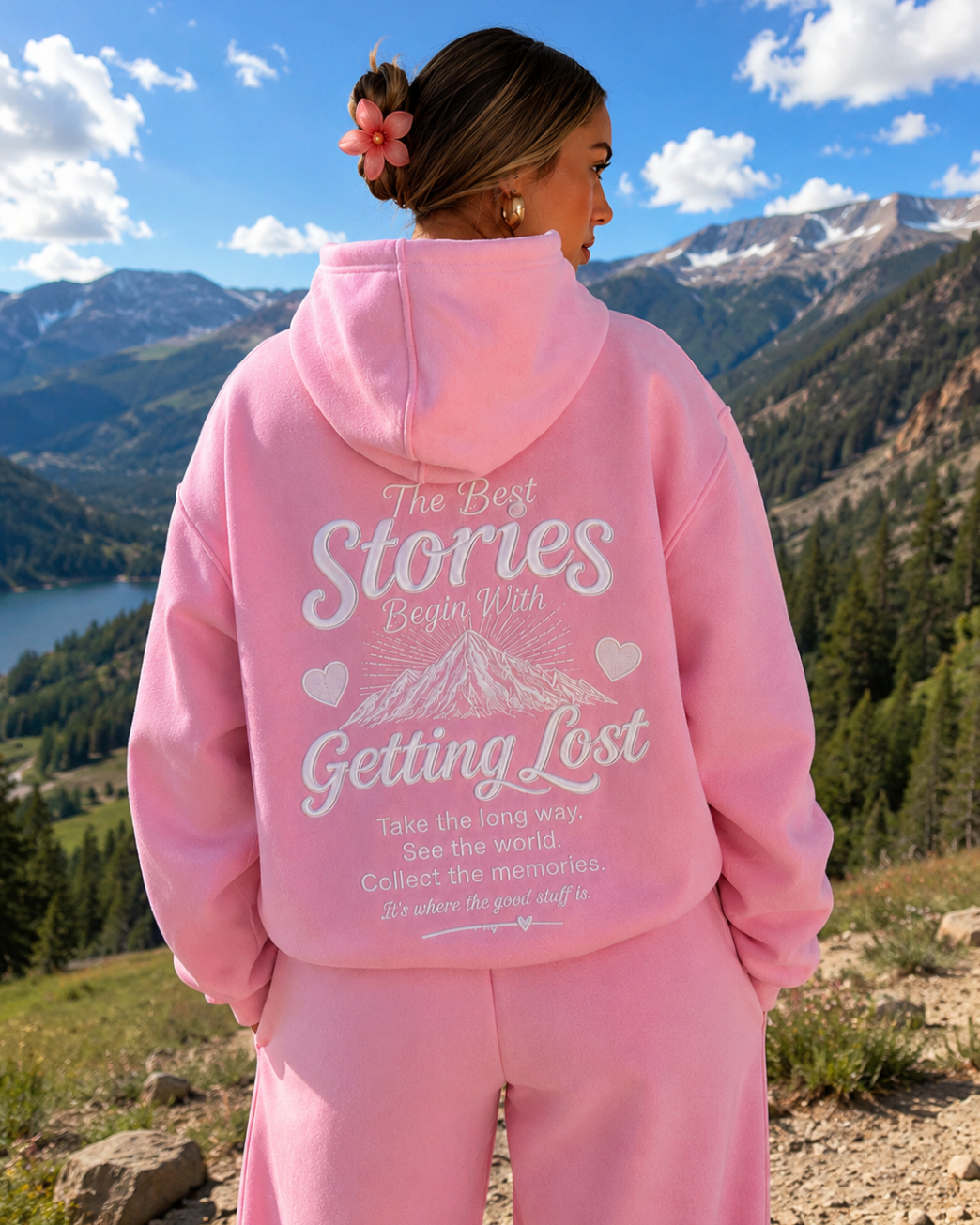 Person wearing a pink hoodie with text in a mountainous landscape