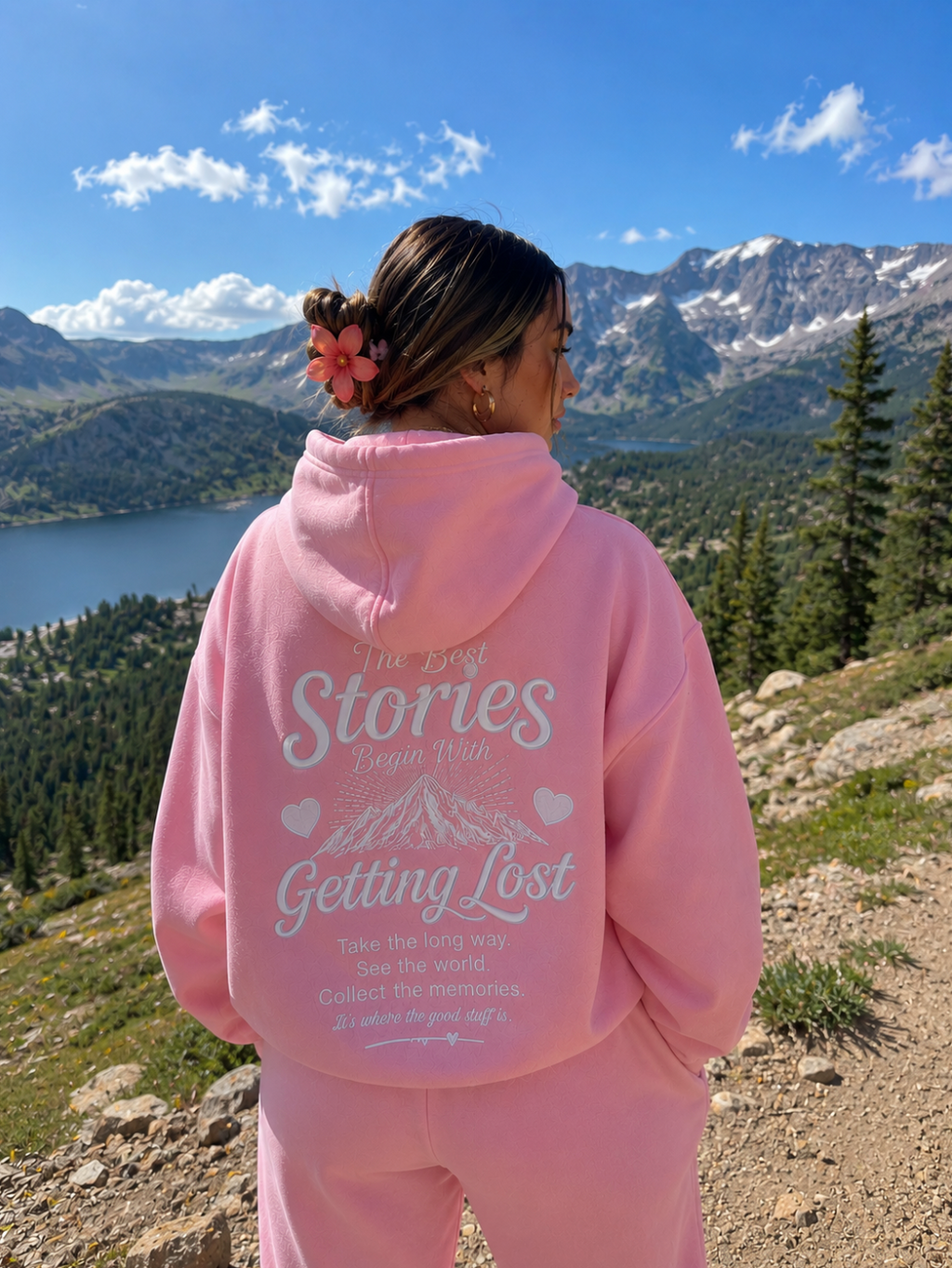 Person wearing a pink hoodie with text in a mountainous landscape