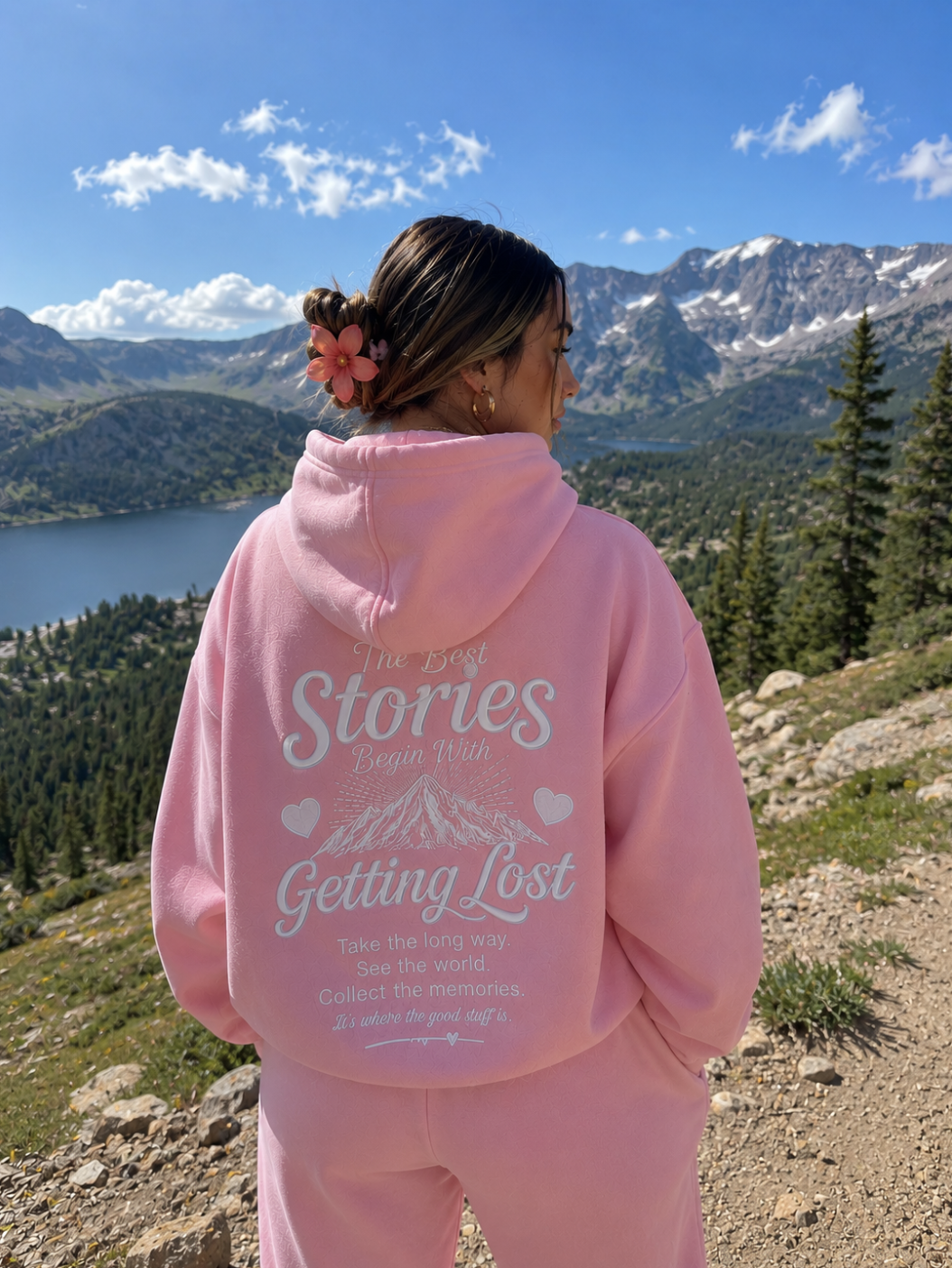 Person wearing a pink hoodie with text in a mountainous landscape