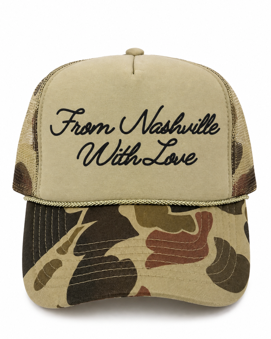 A trucker-style baseball cap with a beige front panel featuring black cursive embroidery that reads 'From Nashville With Love,' and a camouflage-patterned brim and mesh back in tan, brown, olive, and black.