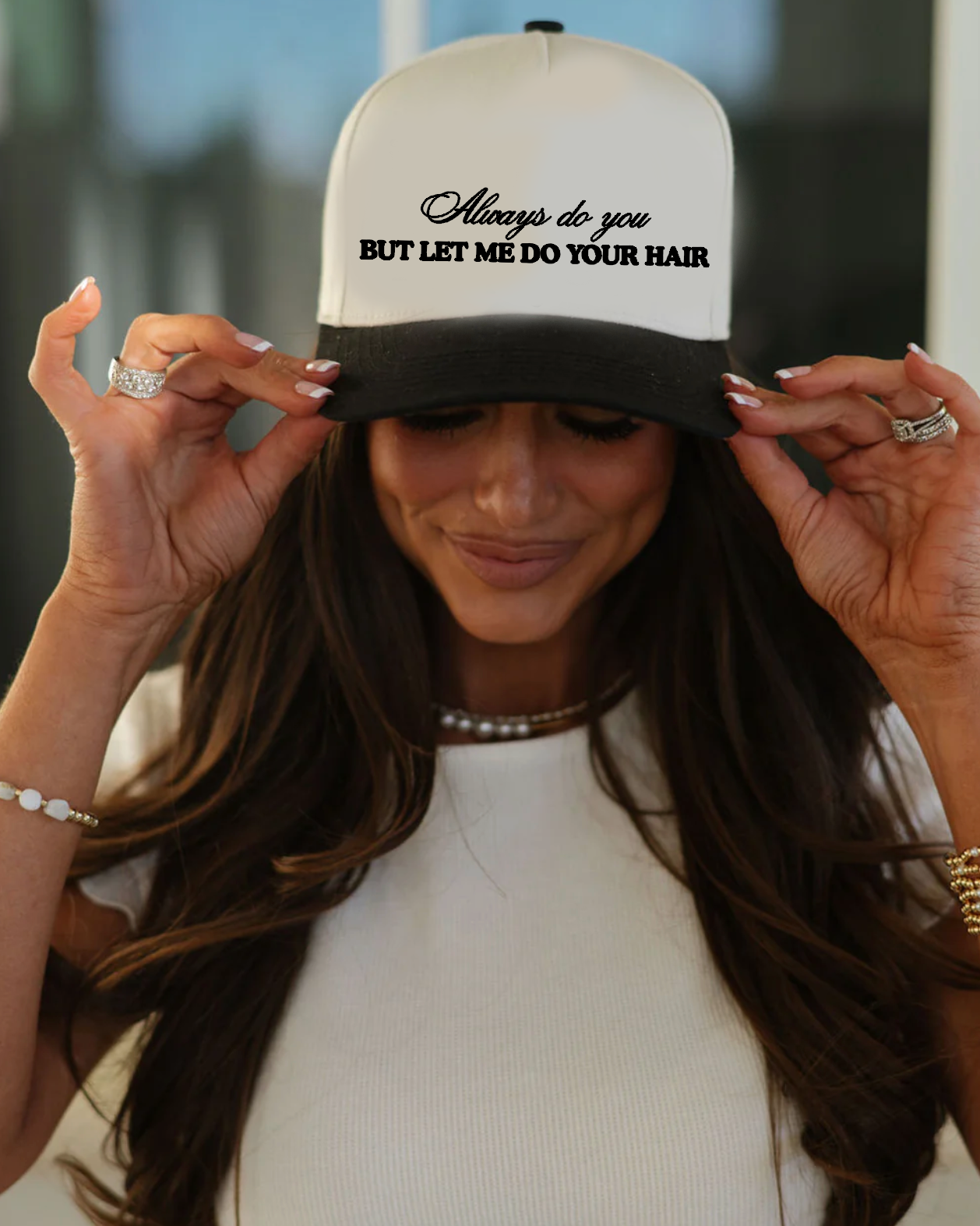 Woman wearing a cap with text and holding her hair, blurred background