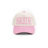 A baseball cap with an off-white crown and a pink brim, featuring the word 'BRIDE' embroidered in pink across the front panels.