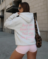 Woman wearing a hoodie with text and pink shorts in an urban setting