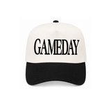 A structured baseball cap with an off-white crown and a black curved brim, featuring the word 'GAMEDAY' embroidered in black across the front. The cap is photographed against a clean white background.